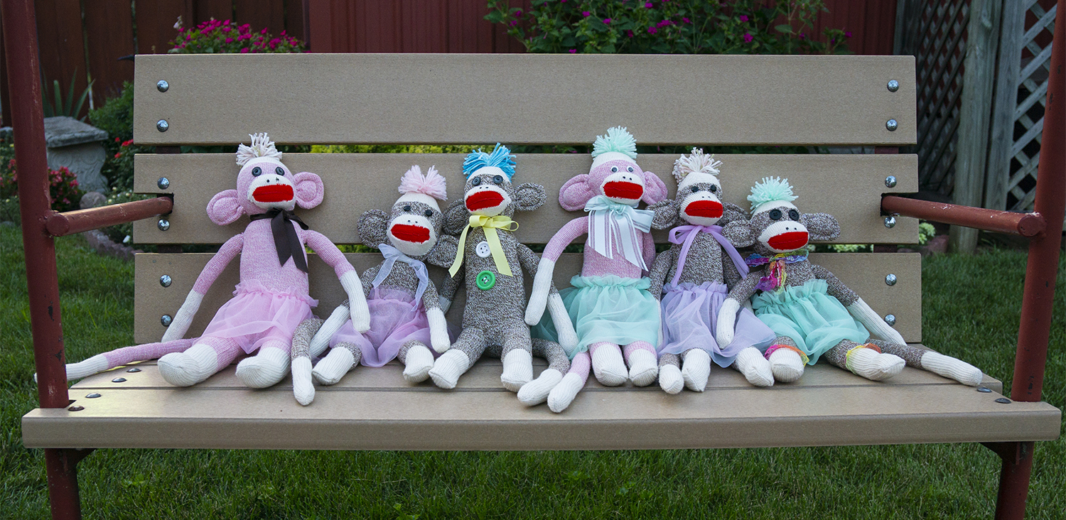 Six sock monkeys sitting on a swing