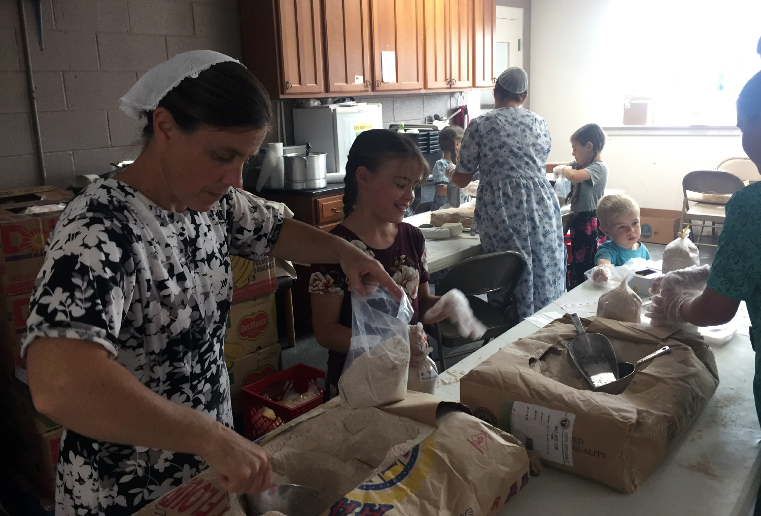 Women and children bagging flour